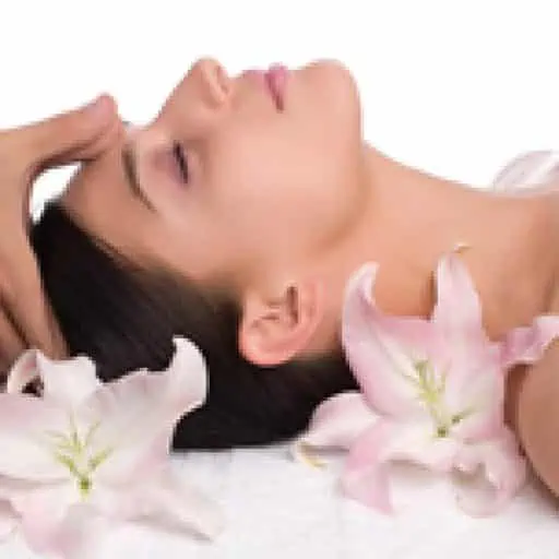 Lady laying down getting head massage with flowers